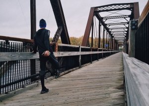 man stretching on a bridge