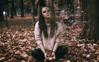 woman sitting in forrest sullenly