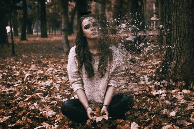 woman sitting in forrest sullenly